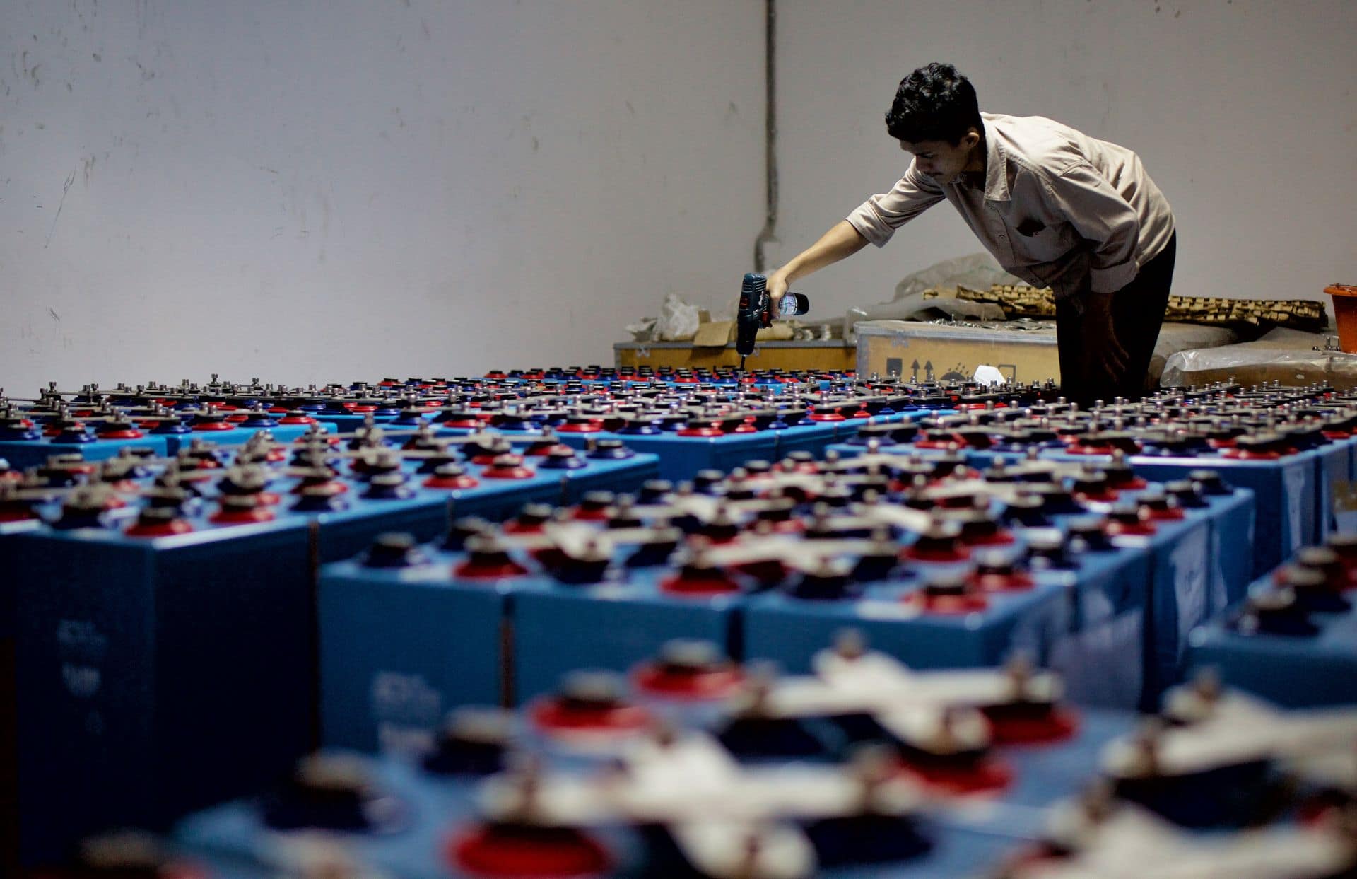 Worker checking a large bank of industrial batteries in a storage facility