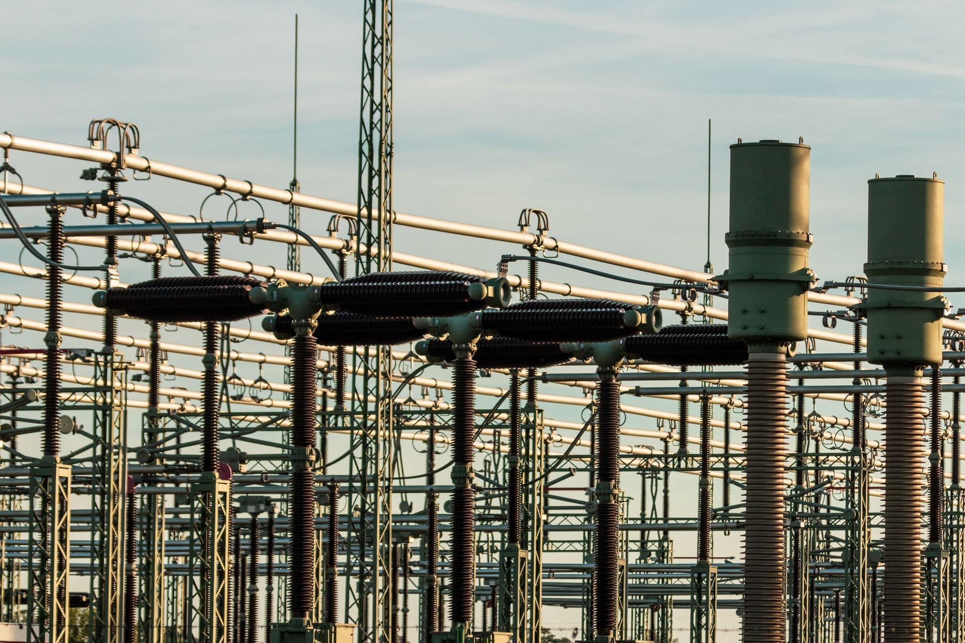High-voltage substation with insulators and busbars against an evening sky