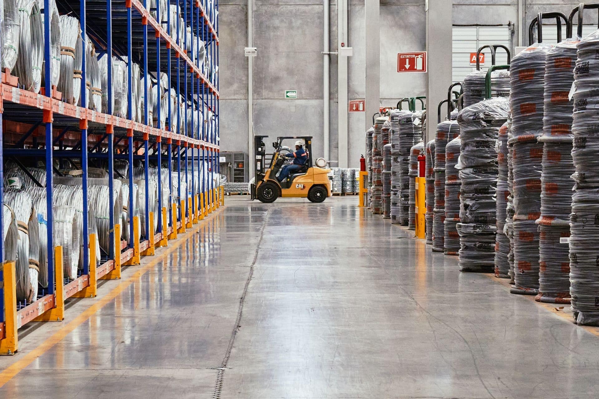 Forklift in the aisle of an industrial warehouse between pallet racking and stacked goods